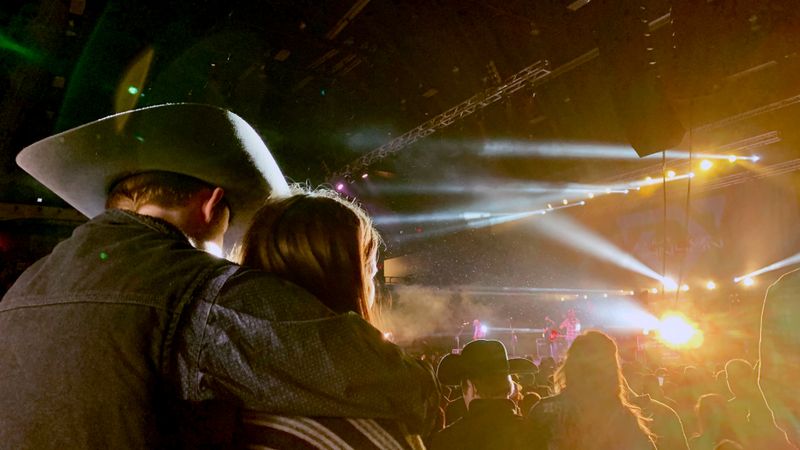 Couple enjoying a vibrant live country concert under bright stage lights.