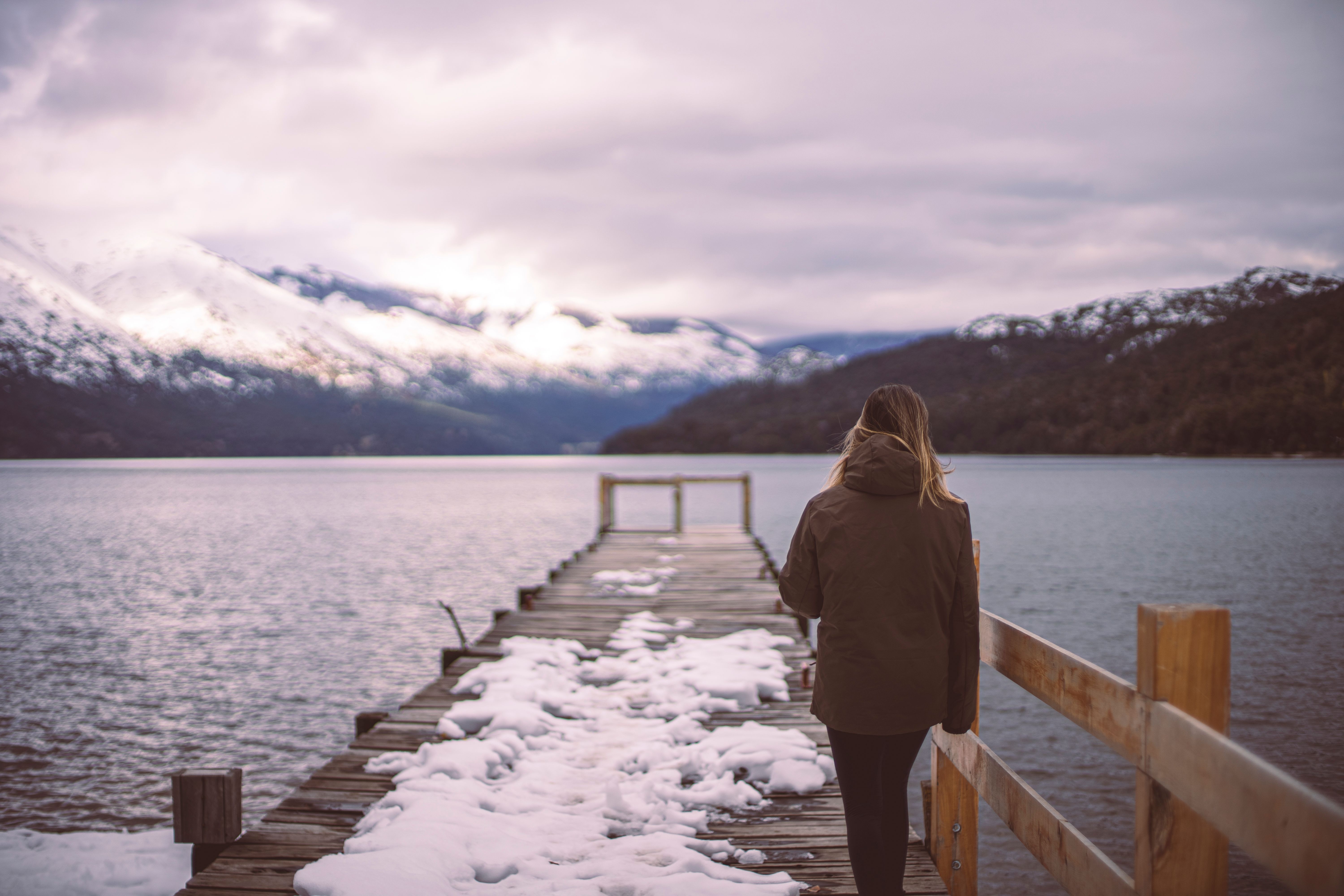 A person in a winter coat walks along a snowy pier in Bariloche, Argentina.