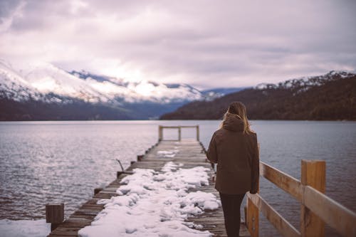 A woman walking on a pier in front of a lake