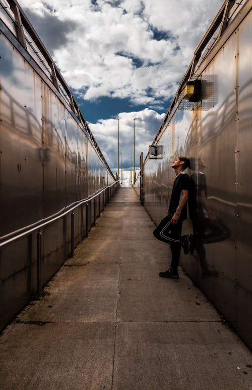 Street Photo of a Man in Black T-Shirt and Pants Leaning on Wall