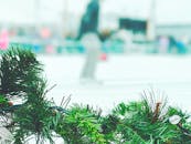 在户外溜冰场附近，一个欢快的冬季场景中悬挂着充满活力的绿色圣诞花环