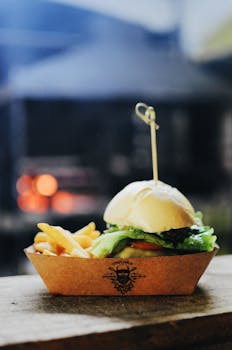 Delicious gourmet burger with crispy fries served in a rustic outdoor setting. Ideal for food lovers.