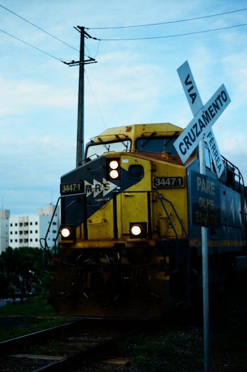 Желтый поезд на стальных перилах возле полюса электричества