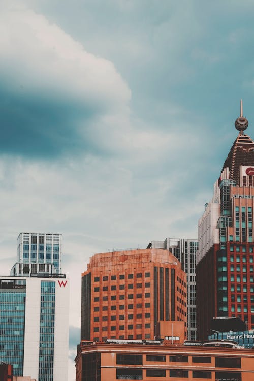 Brown and White High Rise Buildings Under Cloudy Sky