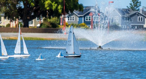 A group of sailboats in the water near a fountain