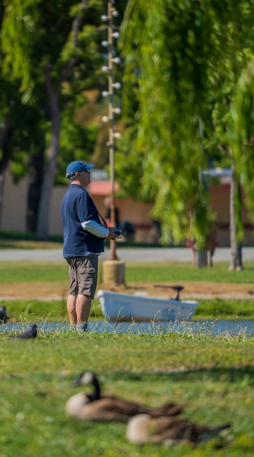 A man fishing in a pond with ducks