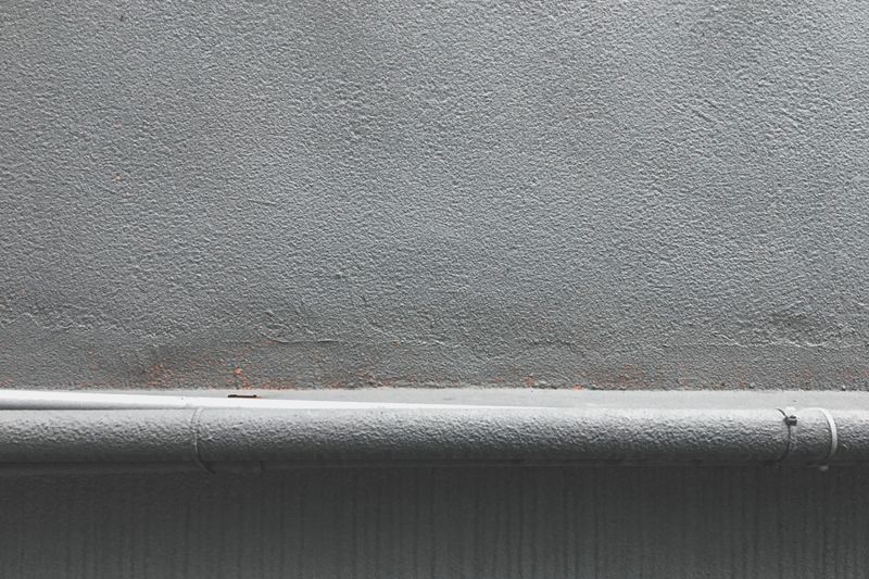 Textured grey wall with a metal plate, lit from the side — photo by H&CO on Pexels