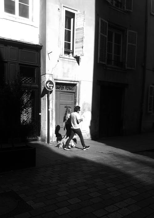 A black and white photo of a man walking down the street