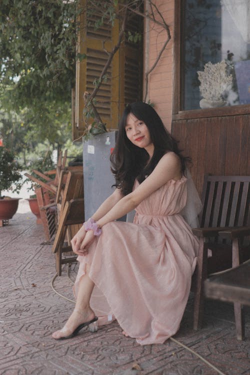 A woman sitting on a bench in a pink dress