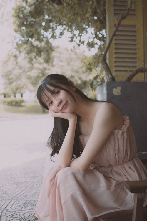 A woman in a pink dress sitting on a bench