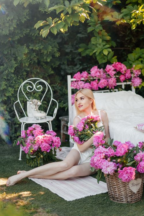 Free A blonde woman in a summer garden, surrounded by pink flowers, enjoying a peaceful moment. Stock Photo