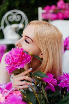 A blonde woman holding vibrant pink peonies, set in a garden scene.