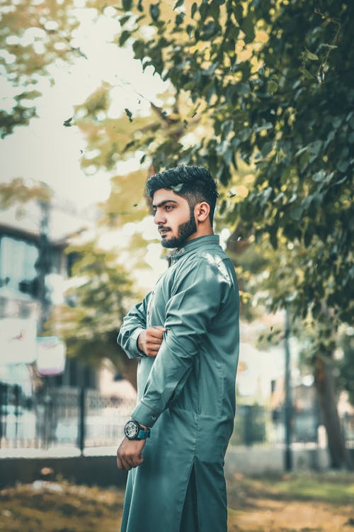 Selective Focus Side View Photo of Muslim Man in Green Thobe Standing Near Tree