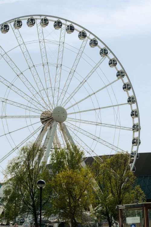 Free A stunning vertical shot of a Ferris wheel against a cloudy sky in Liverpool. Stock Photo