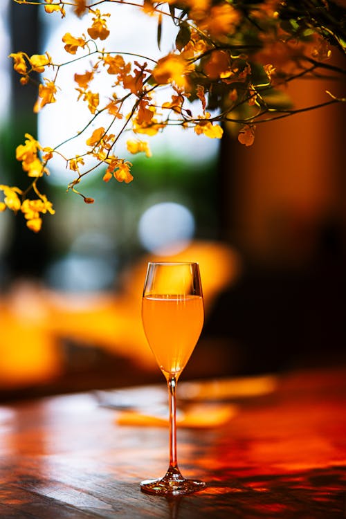 A glass of champagne sits on a table with flowers