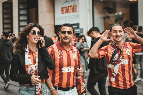 Free A lively group of Galatasaray fans enjoying a day out in the city, showing team spirit with jerseys and scarves. Stock Photo