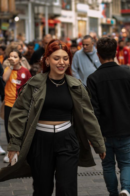 Free Red-haired woman in stylish outfit enjoying a walk through a bustling urban street. Stock Photo