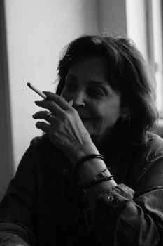 Black and white photo of a woman smoking indoors, capturing a reflective moment.