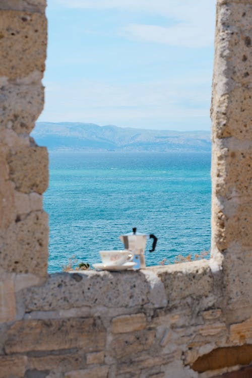 A window with a view of the ocean and a cup of tea