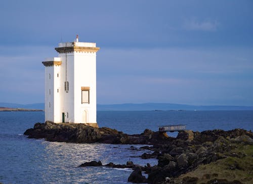A white lighthouse on a rocky island in the ocean
