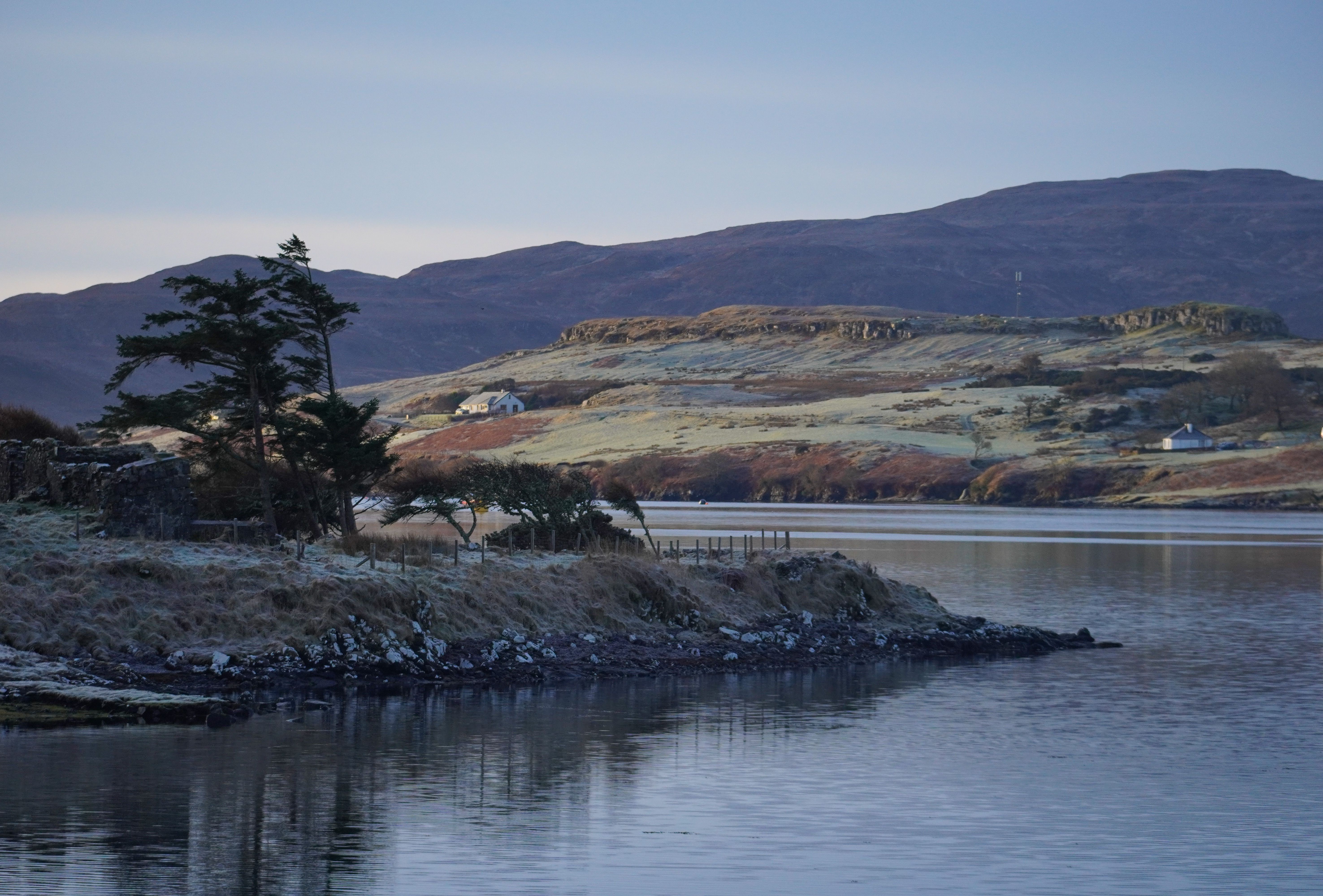 Tranquil frosty morning landscape with gentle river and distant mountains in soft daylight. Peaceful and serene view.