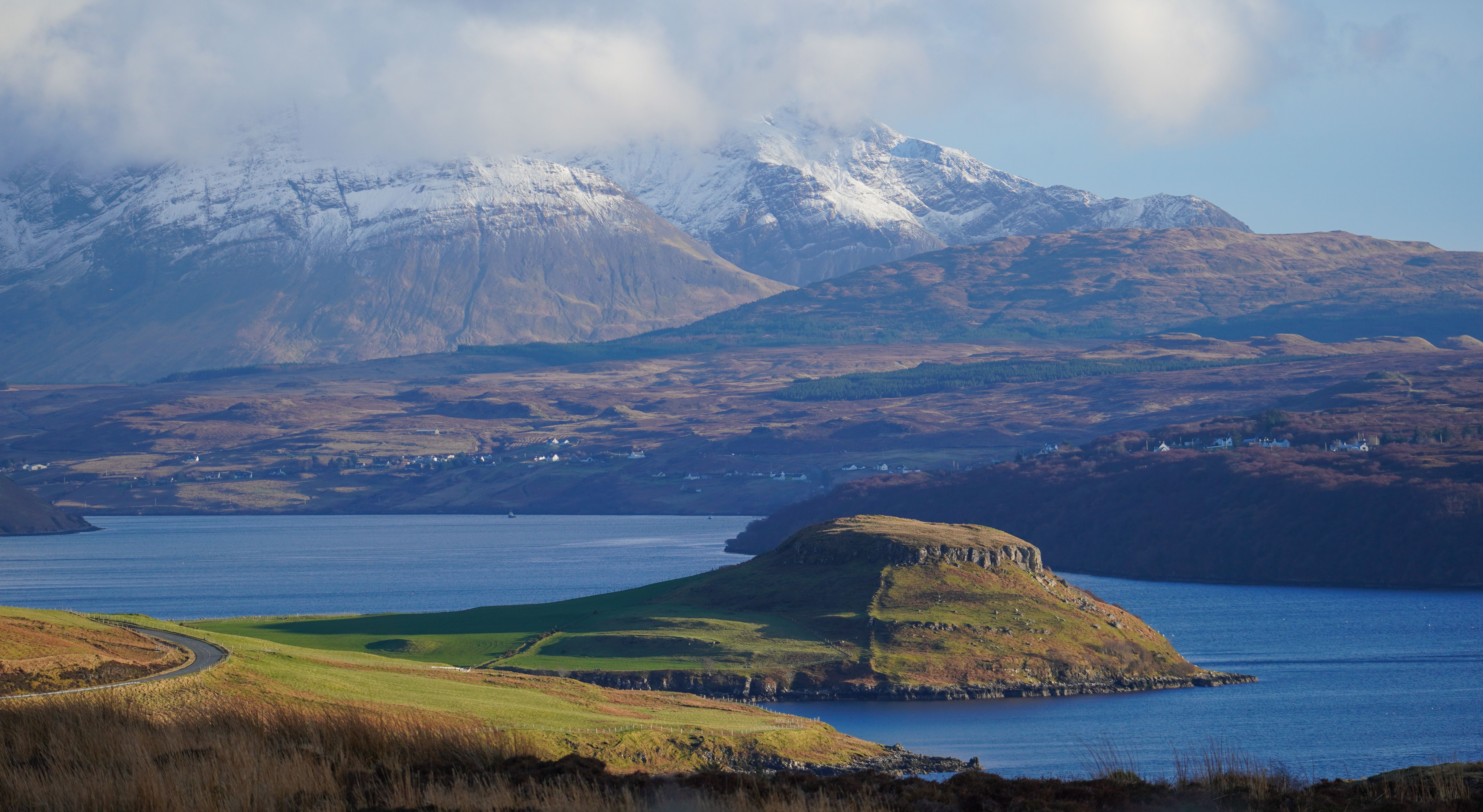 Capture of the stunning Scottish Highlands with snow-capped mountains and lush coastline.