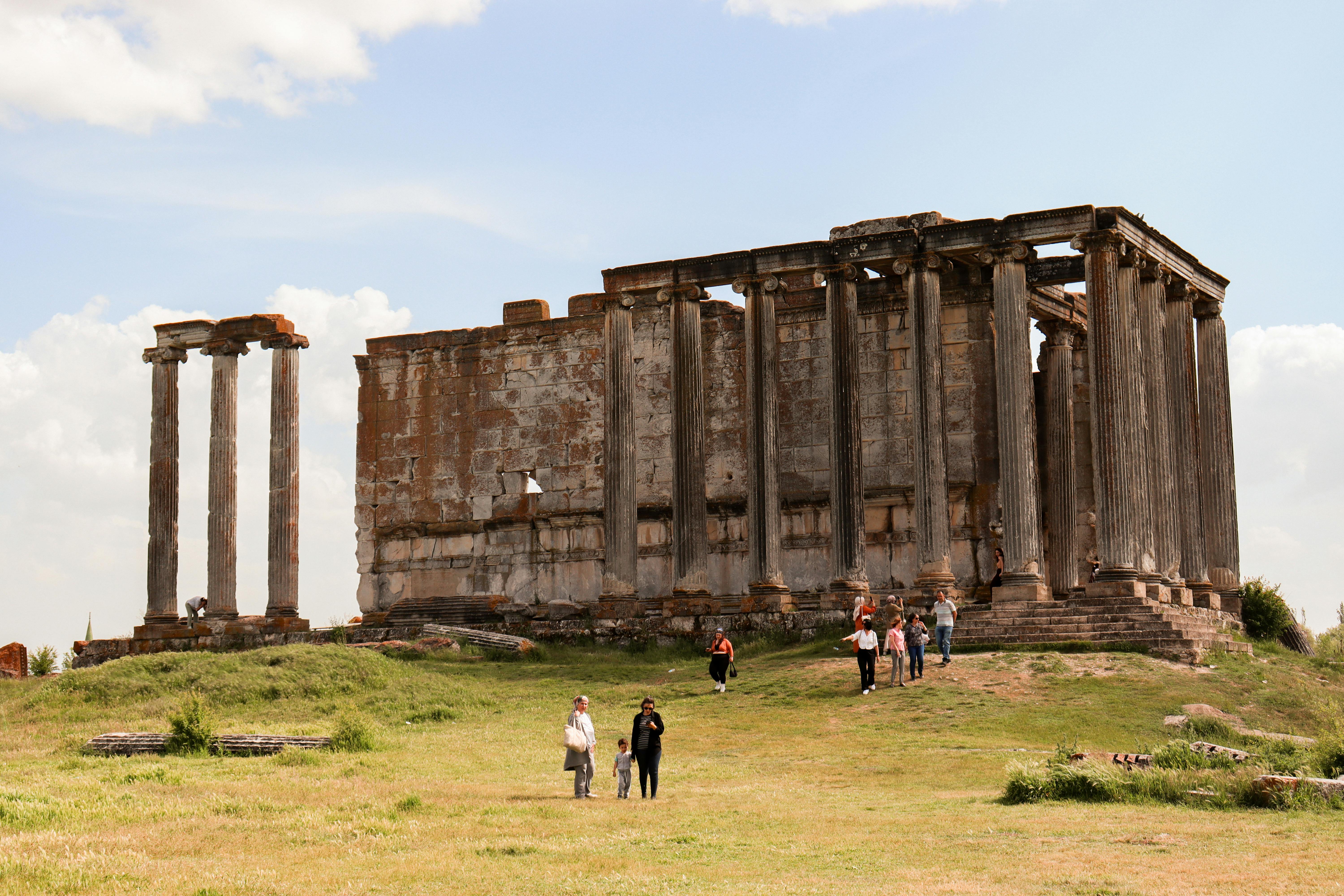 Iconiche rovine dell'antico Tempio di Zeus Olimpico con visitatori che passeggiano attorno al sito storico.