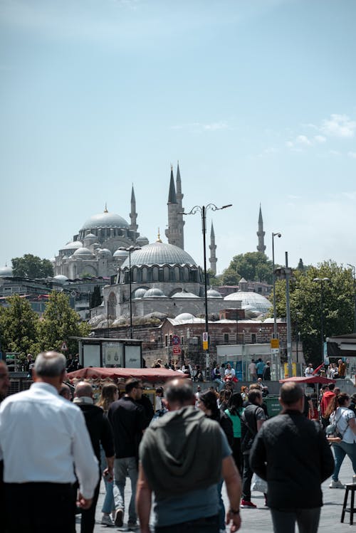 People walking in a city with a mosque in the background