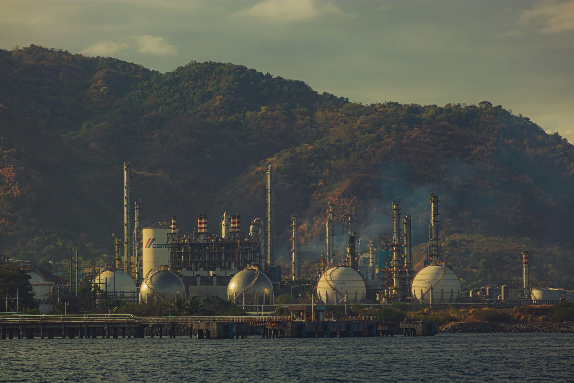 Una gran refinería petrolera con humo de chimeneas bajo cielo nublado