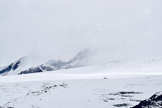 Majestic snow-covered mountain landscape with fog and serene atmosphere.