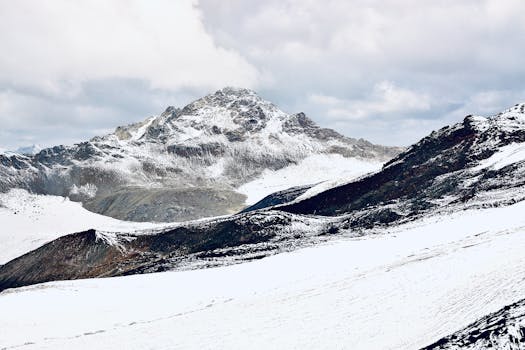 Majestic view of snow-covered rocky mountains under a cloudy sky.