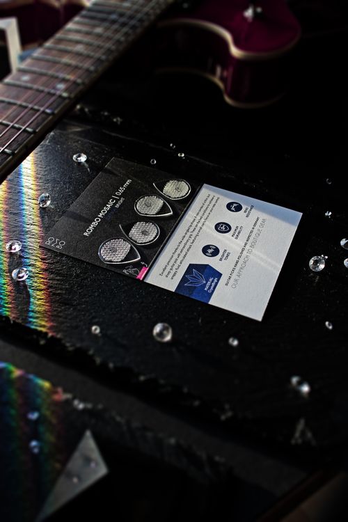 Free Close-up of guitar picks and colorful light reflections on a textured black surface. Stock Photo