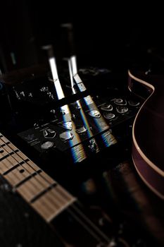 Close-up of guitar picks and switches on audio equipment with reflections and selective focus.