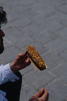 A person holding a piece of grilled corn on the street, showcasing Istanbul's food culture.