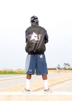 Urban fashion style featuring a young person in denim shorts and jacket outdoors.