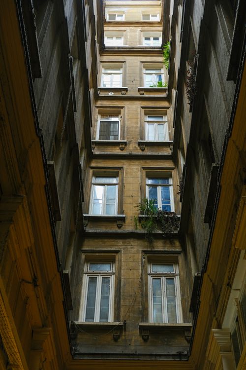 Free A striking upward view of a historical building's courtyard with tall windows and aged architecture. Stock Photo