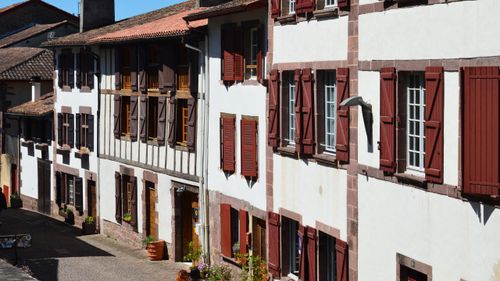 Free Traditional Basque-style buildings with red shutters in a quaint street of Saint-Jean-Pied-de-Port, France. Stock Photo