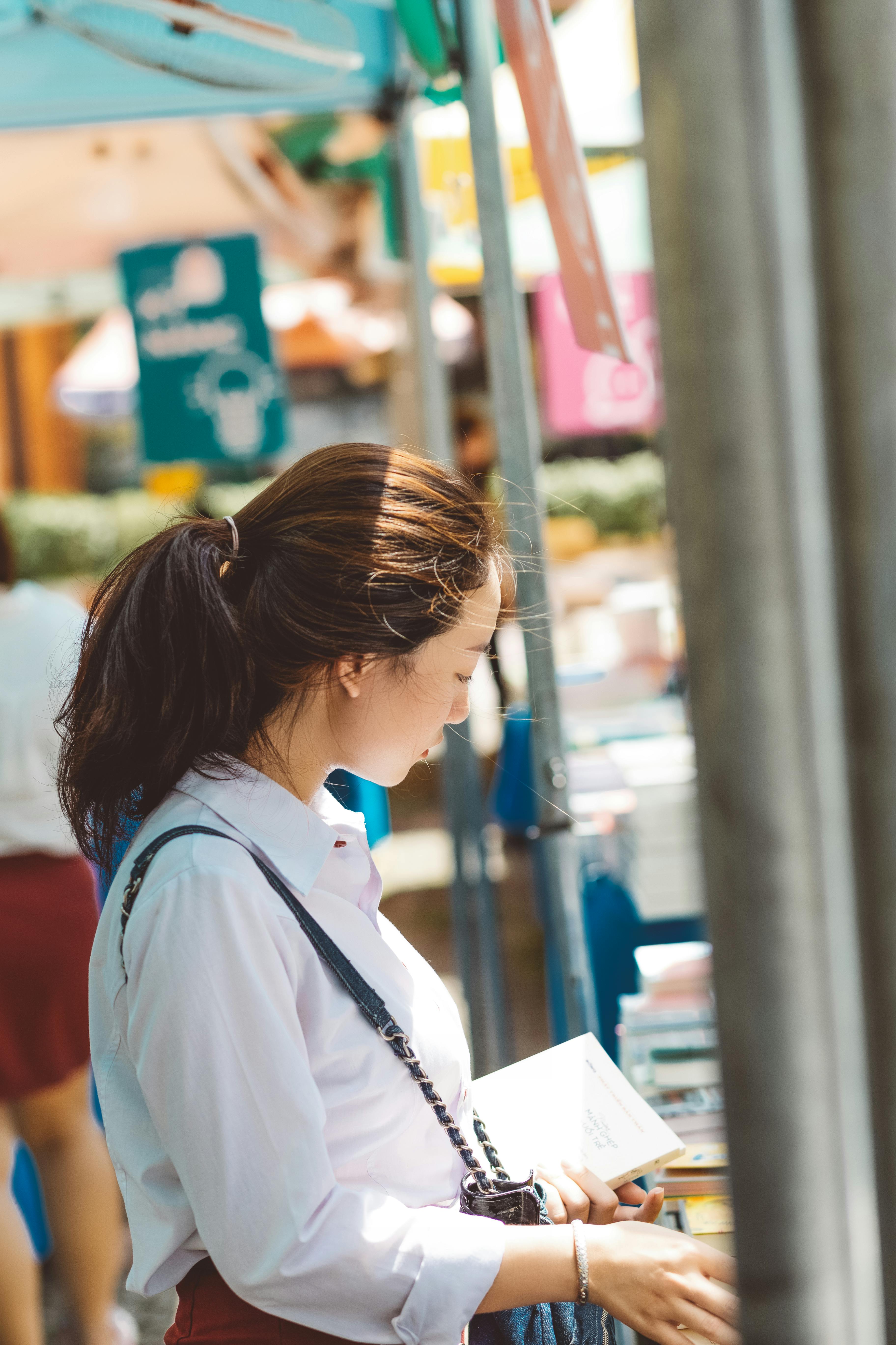 一名妇女在户外市场侧面读书，享受阳光明媚的一天