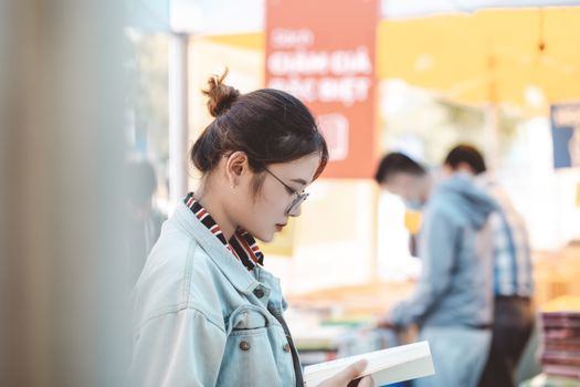 一个女人戴着眼镜在户外市场侧身看书
