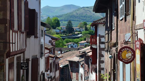 A narrow street with houses and mountains in the background