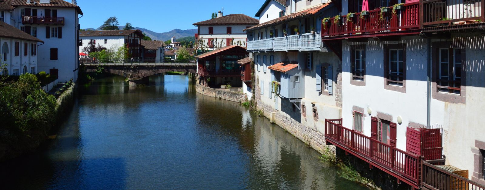 Scenic view of a canal lined with traditional Basque architecture in Saint-Jean-Pied-de-Port, France.