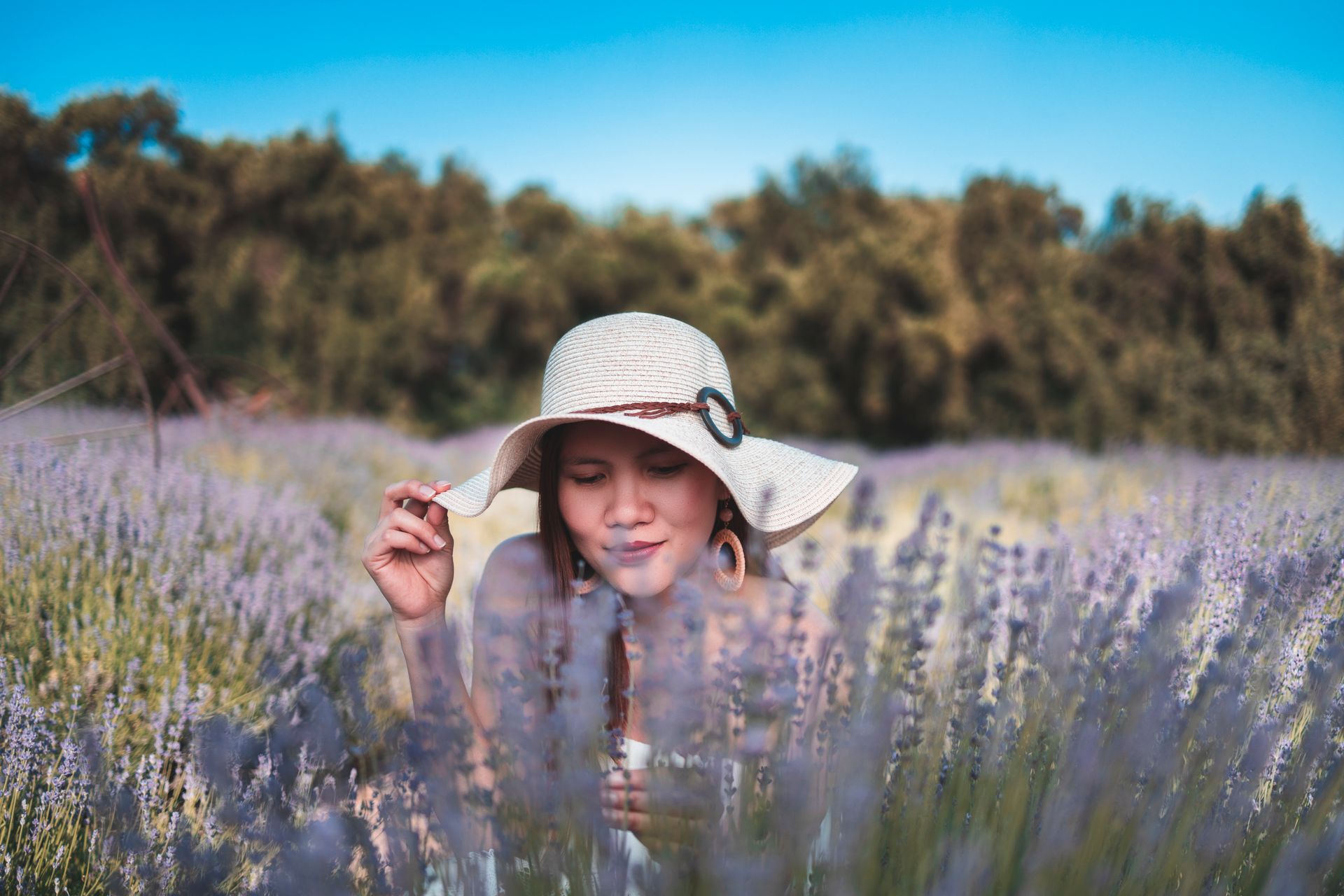 A woman enjoys a relaxing moment in a blooming lavender field on a sunny day.