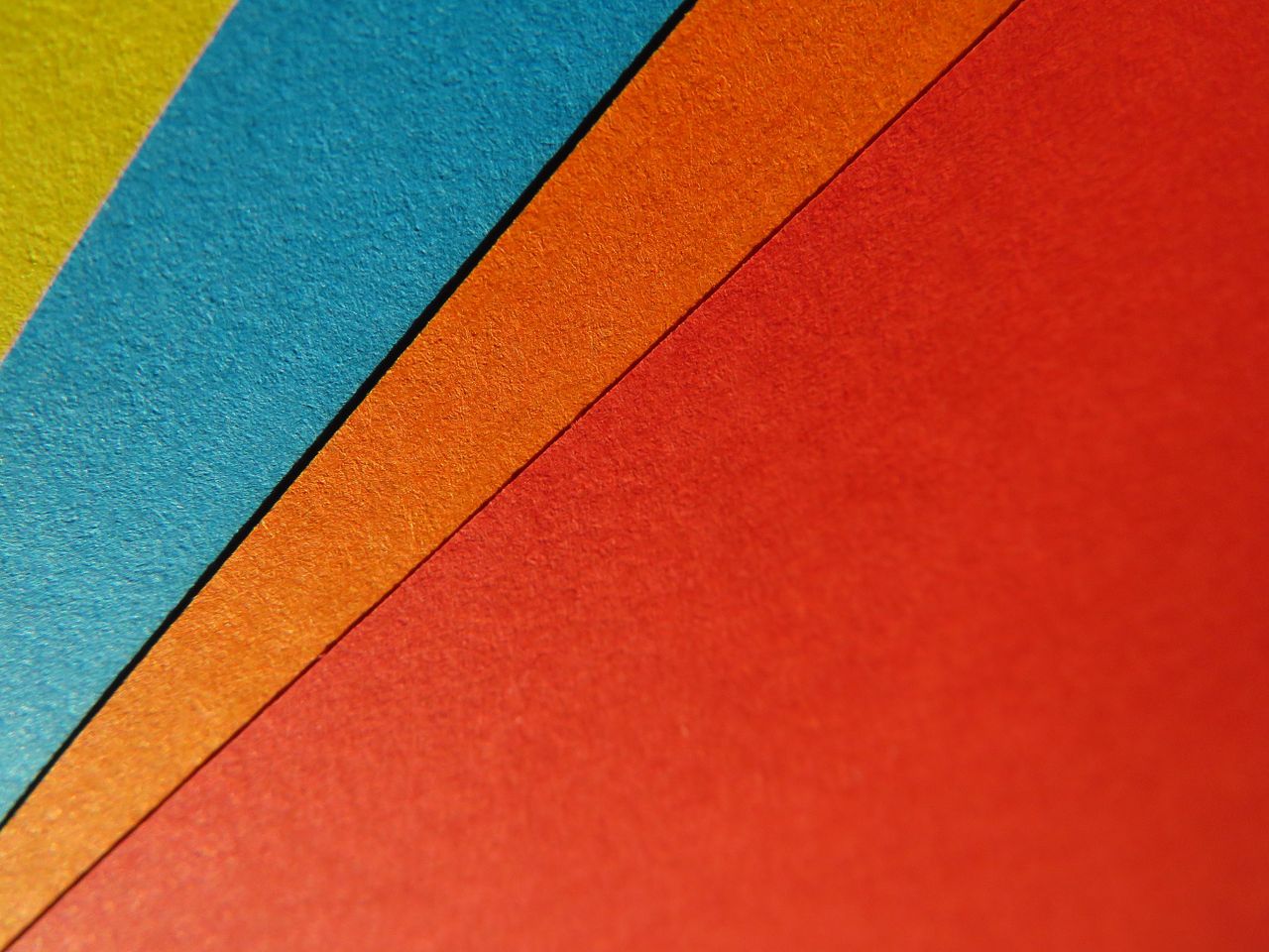 close up of vibrant colorful paper sheets arranged in a geometric patt
