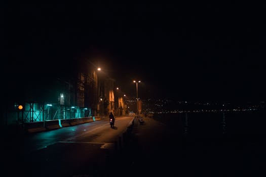 夜晚的街景中，路灯下停着一辆孤独的摩托车，唤起了城市的孤寂