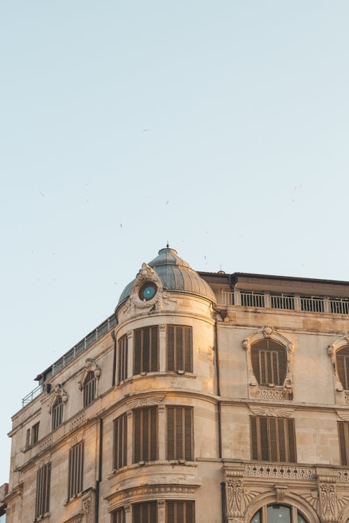 Free From below of aged building with ornamental facade located under blue clear sky in sunny day Stock Photo