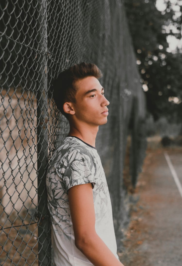 Man Leaning On Chain Link Fence