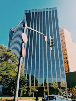 在充满活力的城市景观中，矗立着高大的玻璃摩天大楼，周围设有红绿灯和郁郁葱葱的绿地