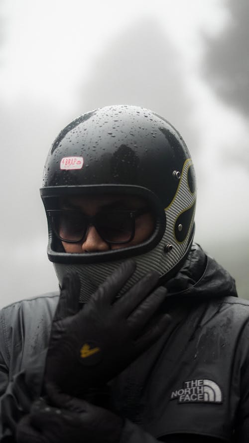 A man wearing a helmet and gloves in the rain