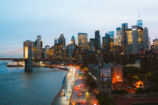 Capture of New York City's illuminated skyline with Brooklyn Bridge at night.