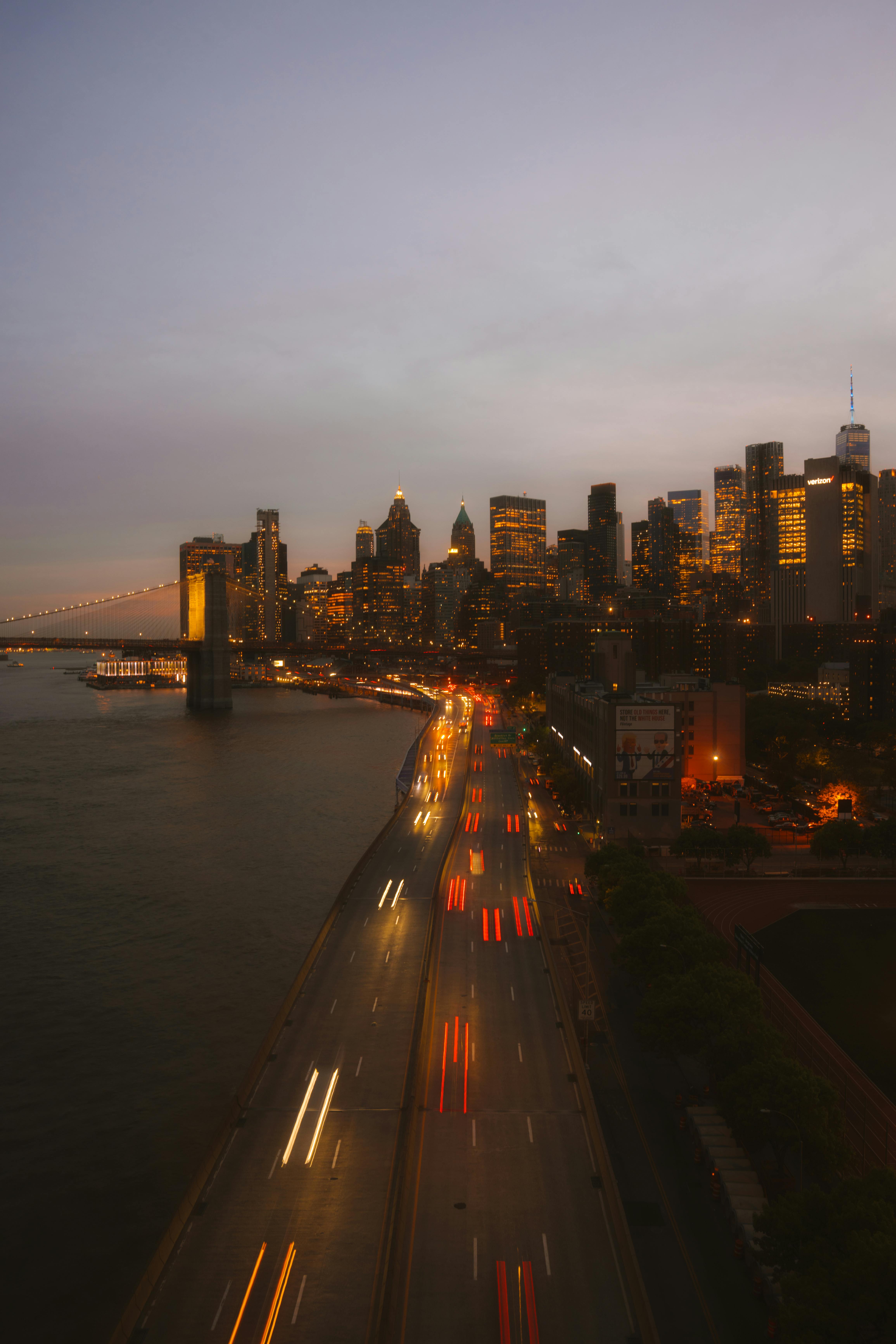 Long exposure capturing vibrant New York City skyline at sunset with blurred traffic lights.
